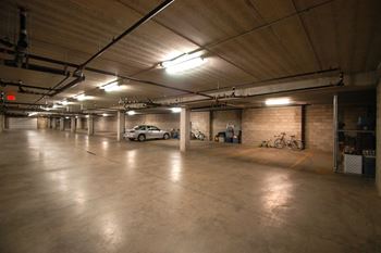 Concrete underground parking garage with overhead lights and parked car